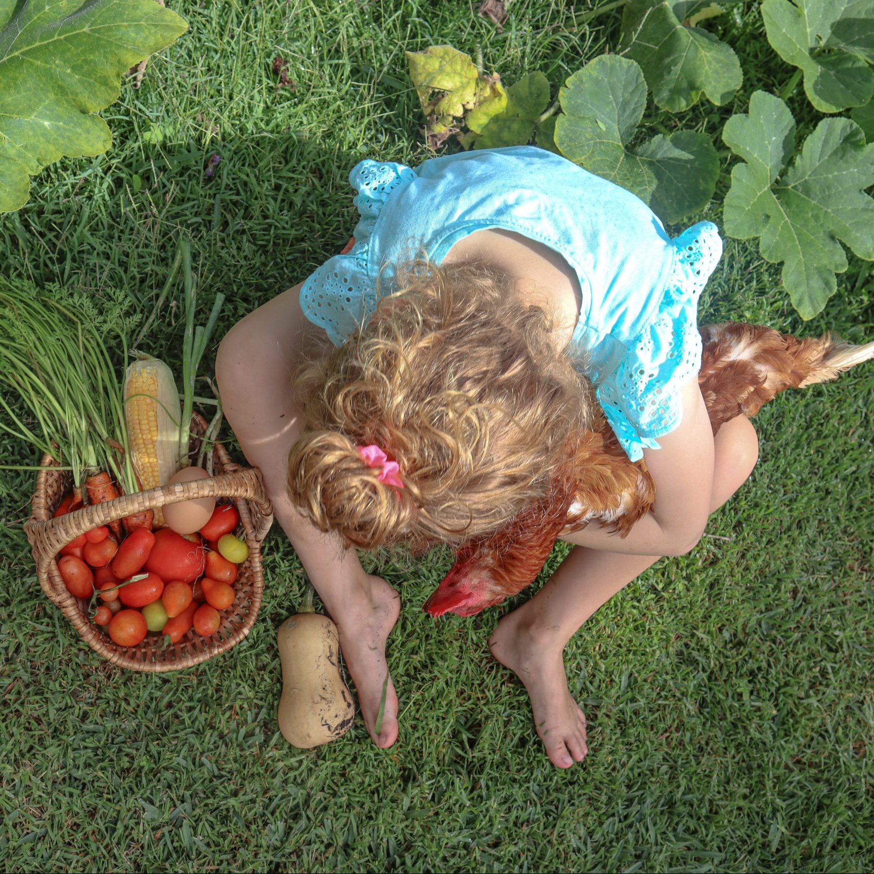 girl in a luscious garden with vegetables and a healthy chicken